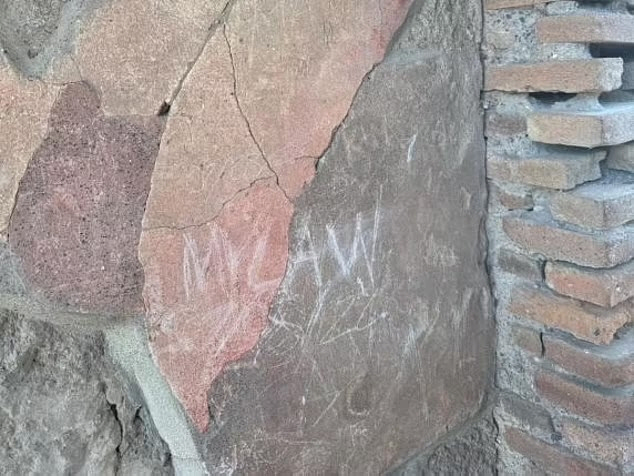 Tourists scribbling family names on the walls of Pompeii's historic site 'Complaint'