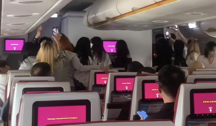 Fans on a plane with a famous boy group on board are making a fuss about taking pictures...It's really pathetic